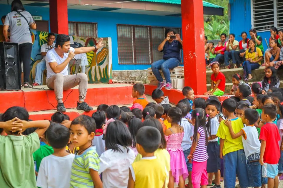 Juneroy entertains the children to a story between a mother goat and her kids.